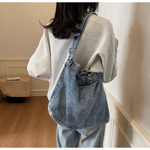 Adjustable wide strap with silver metal buckle on a retro blue denim crossbody bag