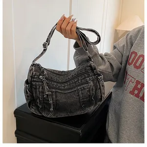 Close-up of vintage washed denim dumpling bag featuring multiple zip pockets and metal hardware