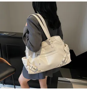 Detail of cream biker tote bag with decorative metal buckles and glossy leather texture