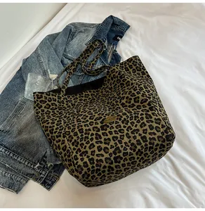 Close-up of leopard print canvas tote bag featuring a handmade metal logo and sturdy texture