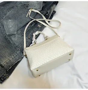 Detail of off-white handbag featuring woven texture and decorative silk scarf handle
