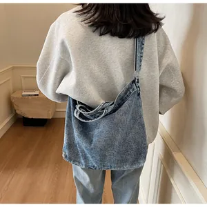 Side view of model wearing a large blue washed denim hobo bag in a minimalist casual style