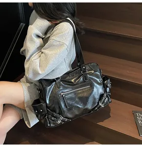 Detail of black Y2K tote bag with rivets and buckles on a motorcycle style shoulder bag