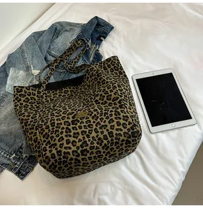 Detail of leopard print canvas tote bag featuring branded patch and dual shoulder straps