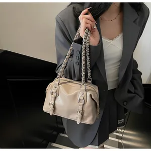 Detail of beige glossy leather Boston bag with silver chain straps and buckle décor