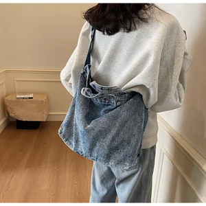 Detail of the oversized light blue washed denim tote bag with wide soft shoulder straps