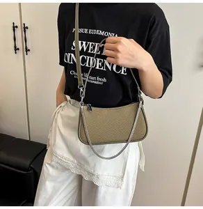 Close-up of woven shoulder bag featuring leather trim and silver metal chain strap