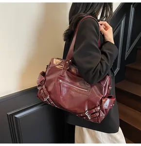 Detail of vintage burgundy tote bag featuring silver rivets and shiny leather texture