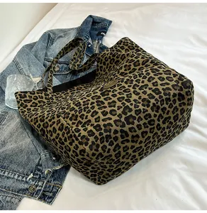 Macro detail of leopard print canvas tote bag with metal handmade label on denim jacket
