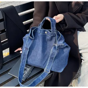 Macro view showing reinforced denim stitching and metal snap closure of the tote bag