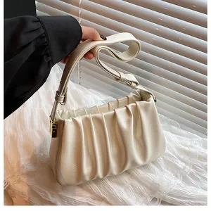 Close-up of creamy white ruched leather bag texture with elegant gold metal buckle detail