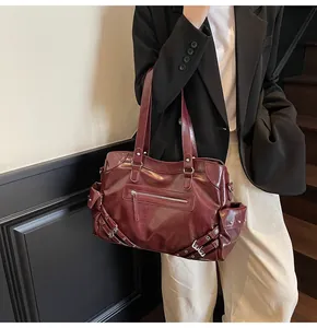 Detail of burgundy leather tote bag showing functional side pockets and silver rivet hardware