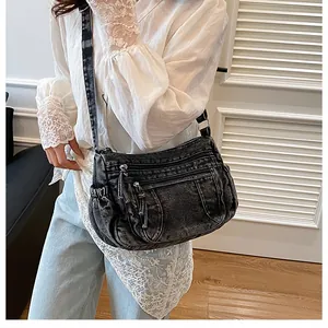 Detail of vintage black denim crossbody bag with multiple zippers and wide shoulder strap