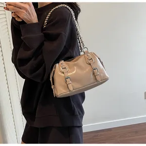 Detail of beige crossbody bag with double buckle straps and silver chain link shoulder strap