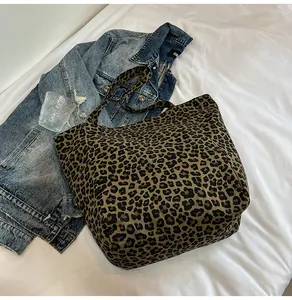 Detailed view of leopard print canvas tote bag styled with denim jacket on white linen