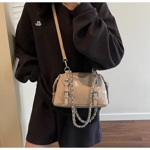 Detail view of khaki crossbody bag featuring decorative silver chains and leather buckles