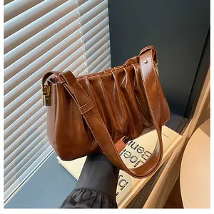 Detailed close-up of brown pleated leather texture and golden metal hardware on handbag