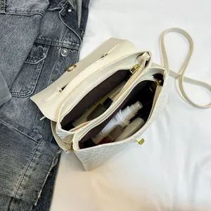 White woven crossbody bag with double zipper and gold hardware showing interior storage