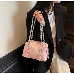 Pink crossbody bag with silver buckles and chain strap on a black blazer model