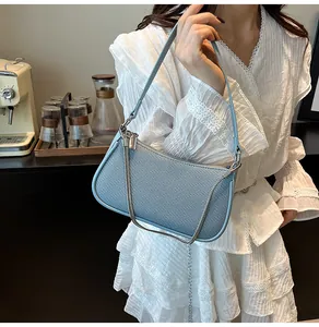 Close-up of a light blue textured shoulder bag with silver chain on a model in white lace