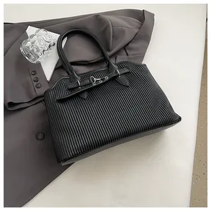 Detail van zwarte geplooide draagtas met leren riem op een grijze pak achtergrond