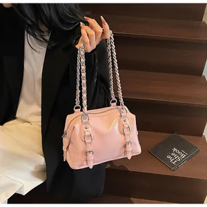 Detailed macro view of glossy pink leather handbag with silver chain strap and belt buckles