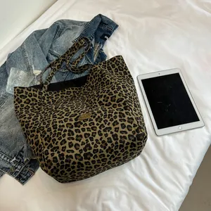 Stylish large canvas tote bag with leopard print and handmade metal badge on white bed