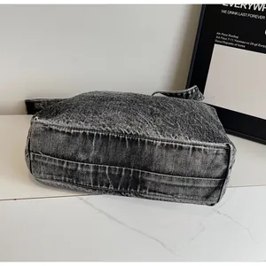 Detail view of the wide bottom and stitching on this retro grey denim tote bag