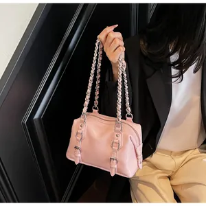 Detail of pink Boston handbag featuring silver chain straps and decorative belt buckles