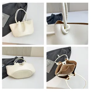 Dettaglio borsa beige con manici annodati, tasche con cerniera e base stabile per organizzazione