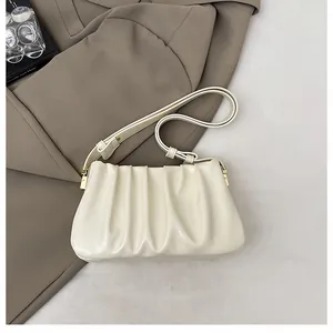 Detail of off-white pleated leather bag with gold hardware and adjustable strap