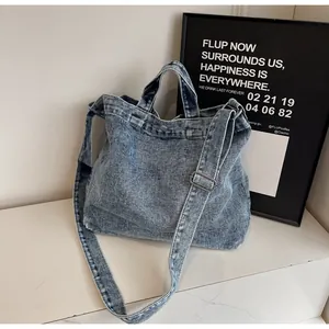 Detail of blue denim tote bag with silver metal buckles and adjustable strap
