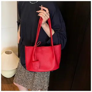 Detail of red lychee grain leather tote bag with a small matching round pouch charm