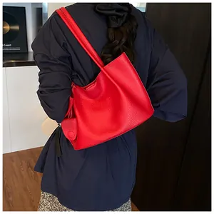 Rear view of a model carrying a vibrant red leather tote bag with pebble texture