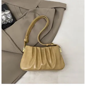 Detail of light brown ruched shoulder bag with adjustable strap and gold buckle