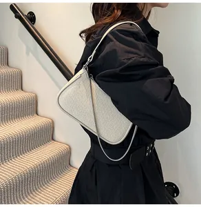 Detailed close-up of ivory woven shoulder bag with leather trim and silver chain strap