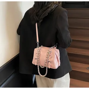 Pink leather crossbody bag with silver chains shown on a model in a modern urban setting