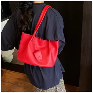 Detailed view of red lychee grain leather tote bag worn on shoulder by a model