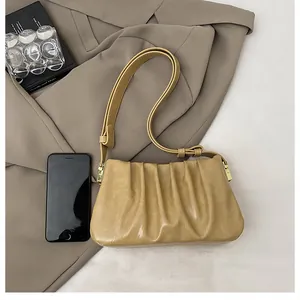 Detail of yellow pleated shoulder bag showing capacity with a smartphone reference