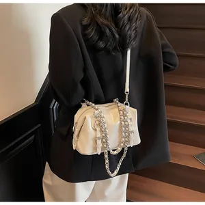 Chic white shiny leather Boston bag shown with crossbody strap on a model outfit