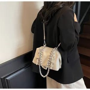 Close-up of beige crossbody bag with silver chain strap worn over a black blazer