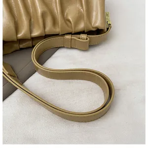 Detail of beige pleated cloud bag showing leather texture and gold metal hardware