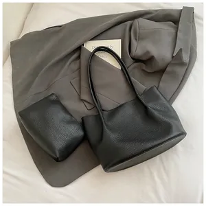 Macro shot of black pebbled leather tote bag with matching inner pouch and slim handles