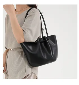 Dettaglio di una borsa tote in pelle nera a pieghe con texture morbida e tracolla sottile
