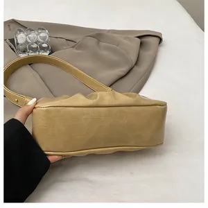 Close-up of the pleat detail and PU leather texture on a khaki cloud shoulder bag