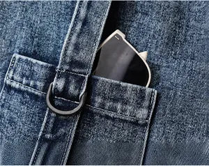 Detail der Denim-Fronttasche mit D-Ring-Schnalle und cremefarbener Sonnenbrille in der Tasche