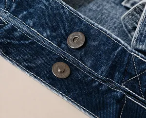 Detailansicht des Magnetverschlusses und der verstärkten Nähte an der blauen Denim-Tasche