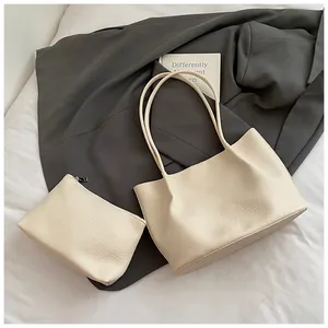Detail of beige litchi grain tote bag set with matching zippered clutch on fabric