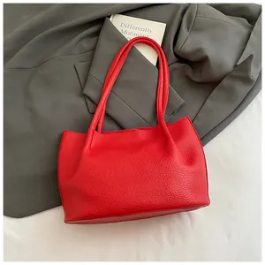Close-up of a bright red tote bag showing detailed lychee grain leather texture and handle
