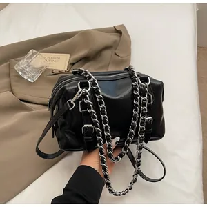 Detail of black glossy PU leather handbag with silver metal chain and buckle straps